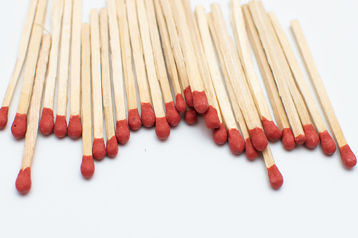 Bunch of matchsticks placed close to each other on a white background which red headed