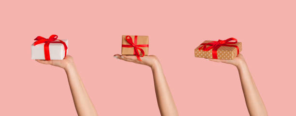 istock Happy holiday. Gift boxes in female hands, pink background. Creative collage. Panorama 1227508623