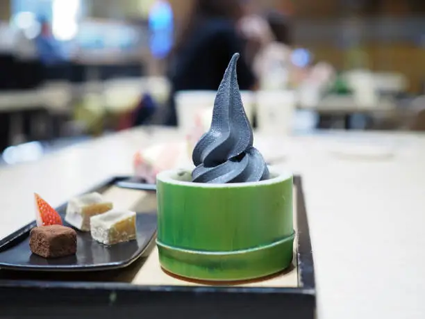 Photo of Black charcoal soft serve ice cream in bamboo shaped bowl served with nama chocolate.