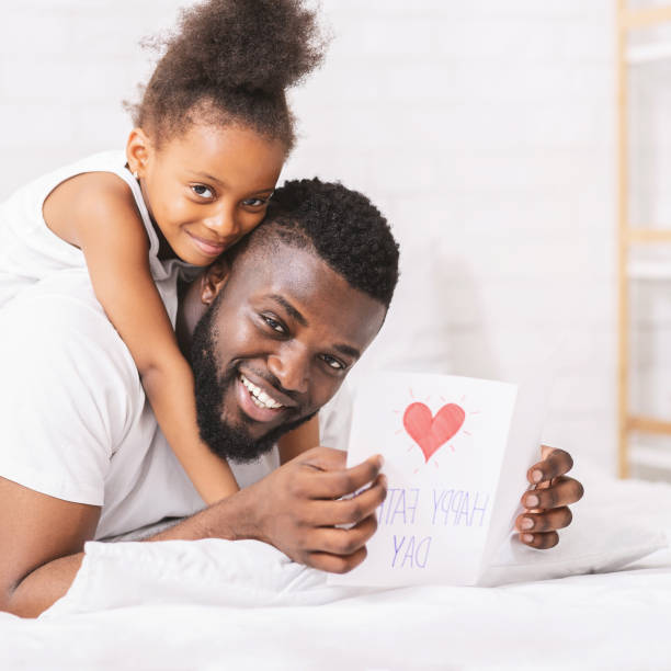 istock African man holding handmade greeting card, daughter hugging him 1227511105