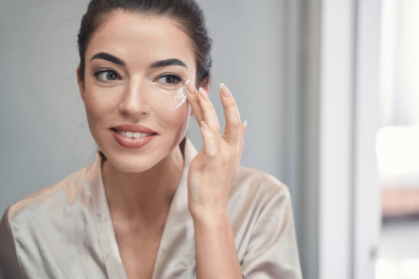 istock Lovely young brunette applying daily cream on her face 1227512311