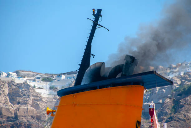 Blue spiral ferry funnel on Grimaldi Cruise Roma emitting white smoke, seen against a clear sky from upper deck with white metal railing.