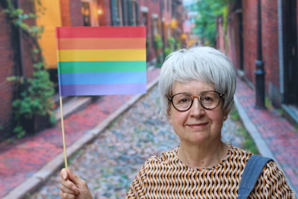 mujer mayor renunciando a la bandera del arco iris - gay pride rainbow flag homosexual fotografías e imágenes de stock