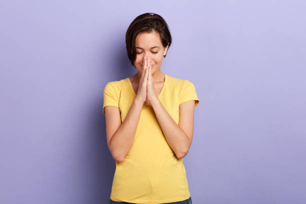 istock positive cheerful woman keeps hands in praying gesture 1227516173