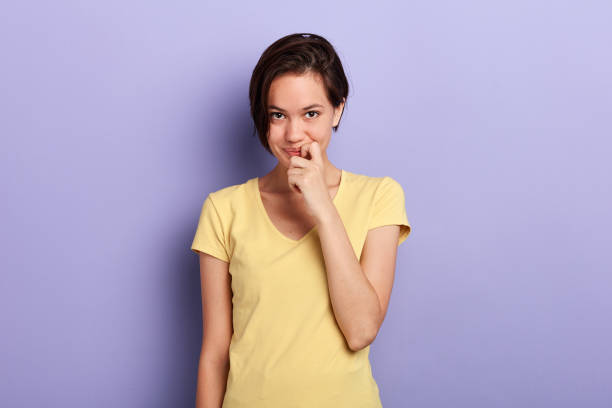 istock cheerful awesome pretty girl looking at camera biting nails over blue background. 1227516287