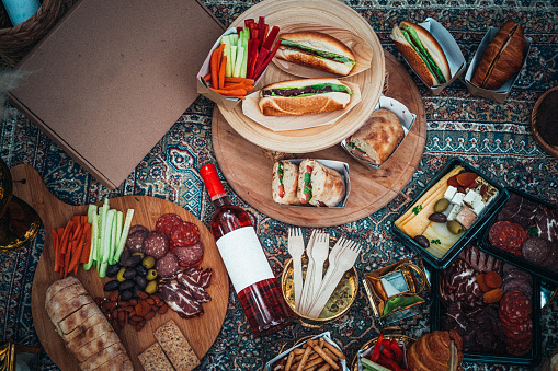 Picnic setup of food and drink on a blanket from above