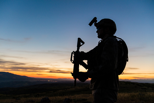 Silhouette of standing soldier against sunset sky