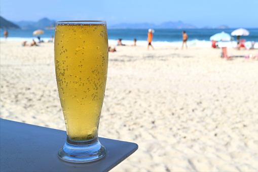 Glass of cold draft beer against sunny Copacabana beach in Rio de Janeiro, Brazil, South America