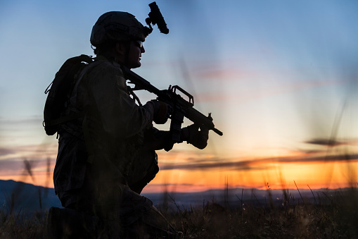 Silhouette of an kneeling soldier against sunset sky