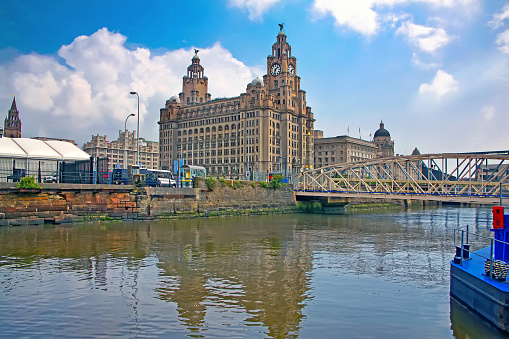 Liverpool waterfront with the The Royal Liver Building in the foreground & reflections of the city in the Mersey river, Liverpool, England, UK.