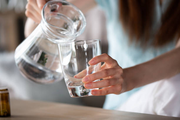 istock Woman pouring water from a jug into a glass, taking supplements 1227520165