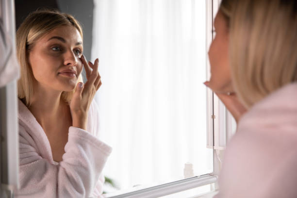 istock Woman applying face cream in front of mirror 1227521787
