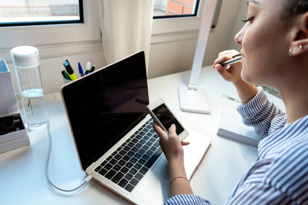 istock Young woman sitting at a laptop and using a smartphone. 1227522288