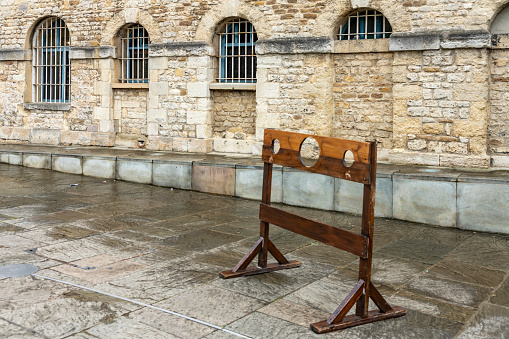 A set of stocks on display outside Oxford Gaol beside a public footpath.