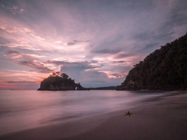 Sunset in Nusa Penida, Indonesia. Image from the shore, colorful sky, clouds, and a starfish as well as the mountains