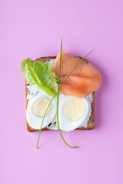 sanduíche com queijo mascarpone, ovos, salmão em um fundo rosa. vista superior. - sandwich breakfast boiled egg close up - fotografias e filmes do acervo