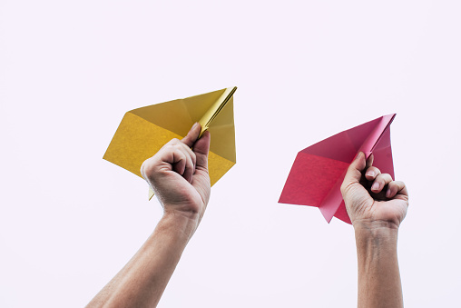 Adult hands holding paper airplanes and ready to take off against overcast whether