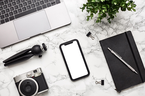 Mockup of smartphone with white screen on marble textured background. Flat lay, top view workspace stock photo