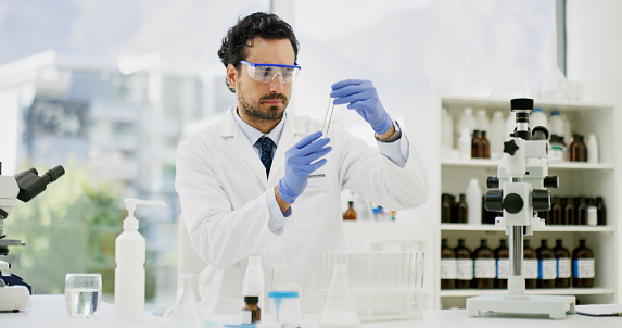 Shot of a young scientist examining a test tube in a lab