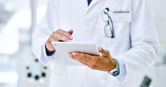 Closeup shot of an unrecognisable doctor using a digital tablet in a lab