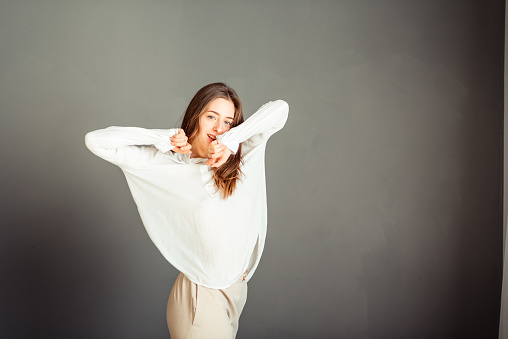 Young girl in a white shirt on a gray background. French woman in white blouse on a background of gray walls. Without retouching and makeup.