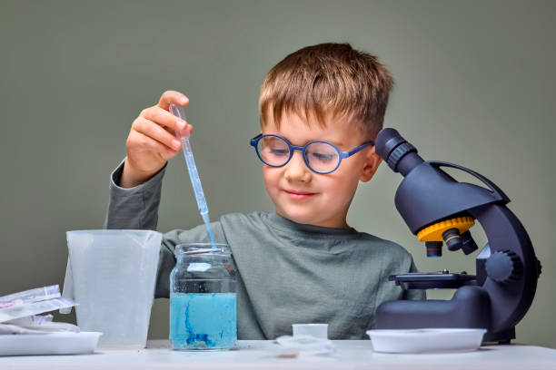 Studying remotely online. Toddler genius baby. Technology and science concept. Kid studies biology and chemistry at home school. School education. Pupil studies natural sciences. Elementary school