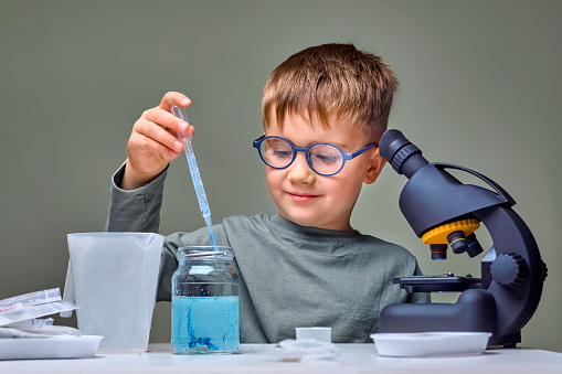 Boy playing in testing laboratory. Kid near microscope and test equipment at home laboratory. Learn for future. Child plays at test laboratory. Little genius child. Elementary school kid
