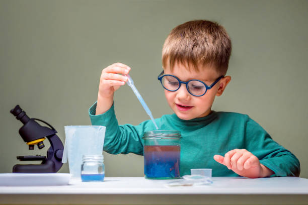 istock Small boy studies chemistry. Testing tubes with liquid for research. Learn for future. Biology science. Preschooler at home. Little genius child. Pupil using microscope. Young confident scientist 1227545235