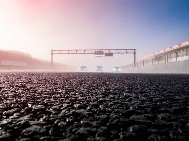 Photo of Speed cars at the start line with green light signal on. Cars ready to start on a speed circuit. Morning fog on the race circuit track. Fast cars with the lights off. Ready set go. Race Drive Concept