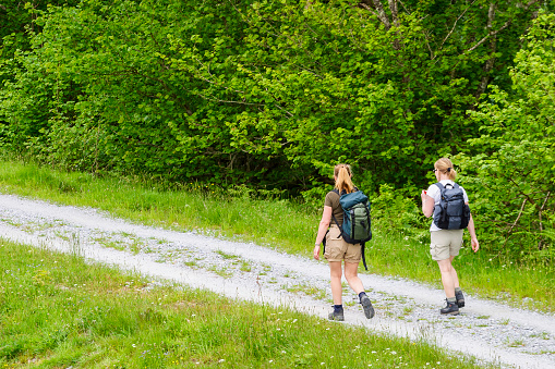 Caledonian canal, United Kingdom - May 31, 2015:  Young women walking on a path with lush trees
