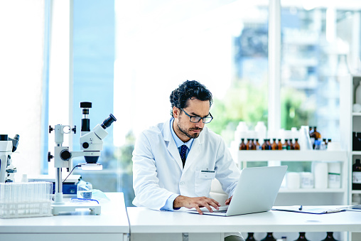 Shot of a young scientist working on a laptop in a lab