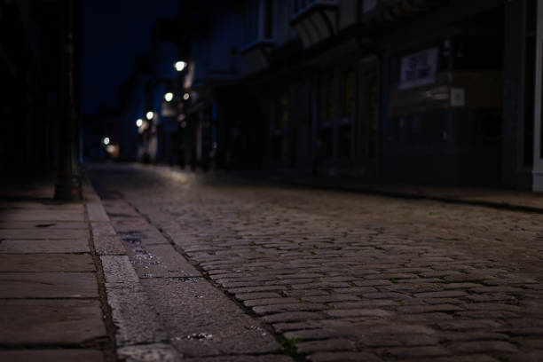 Empty Cobblestone street in Canterbury at night Low to the ground view of Canterbury grey cobblestone street with bokeh background of street lights canterbury england stock pictures, royalty-free photos & images