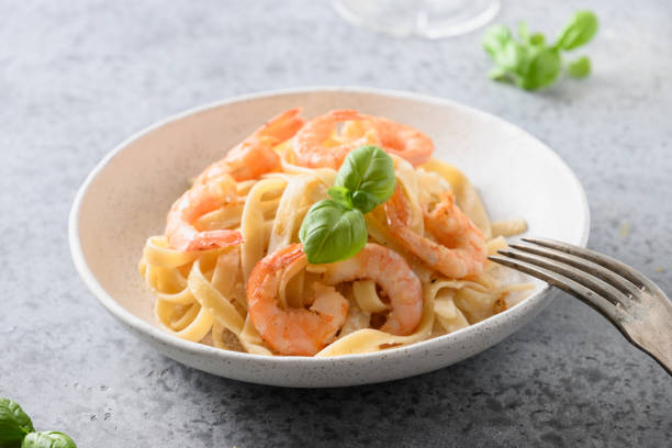Italian pasta fettuccine with shrimps on gray. Close up. Italian pasta fettuccine with shrimps in white bowl on gray table. Close up. food state preparation shrimp prepared shrimp stock pictures, royalty-free photos & images