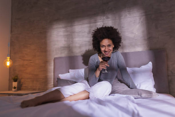 istock Woman drinking wine in bed 1227558136