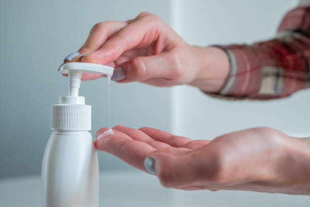 istock Woman squeezing out antiseptic gel on palm - close up side view 1227558372
