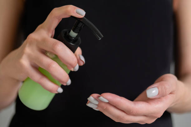 istock Woman squeezing out antiseptic gel on palm - close up front view 1227558574