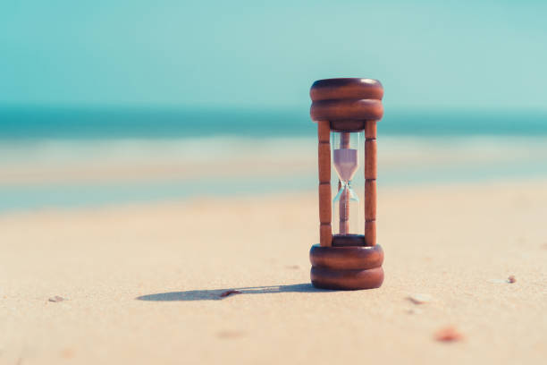 istock Hourglass on sand beach with blue sky background. 1227558817