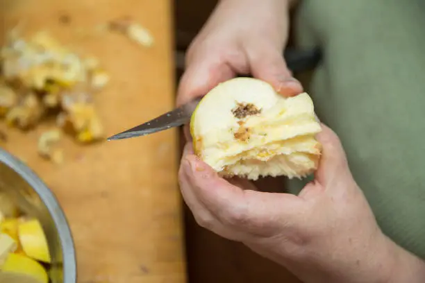 Woman peels quince . Quince fruit peeled with hands on a light background with space for an inscription