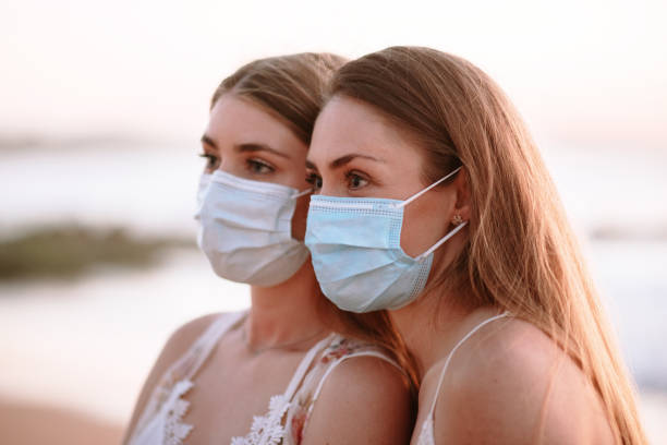 istock Two young women wearing protective face masks at the beach 1227565240