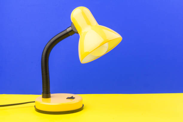 istock Yellow desk lamp isolated on blue and yellow background 1227565576