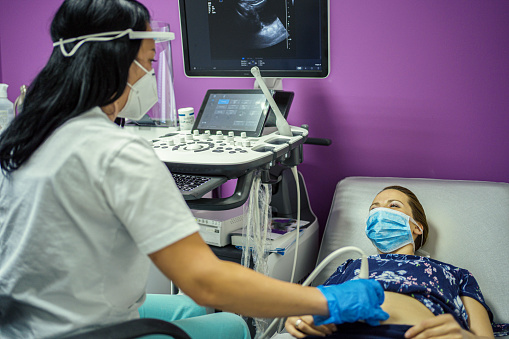 Woman with face mask at ultrasound examination during COVID-19