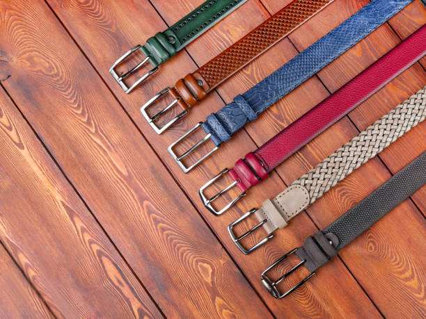 A set of different trouser belts on a plank background. Close up, top view. Abandoned varnished wood