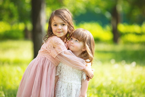 Two small beautiful girls children together happy play and laugh in nature