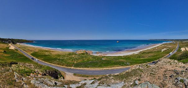 Panoramic view of St Ouens Bay wth the FiVe Mile Road, part of the sand dunes, the beach with waves and sunny blue sky. Jersey, Channel Islands, uk