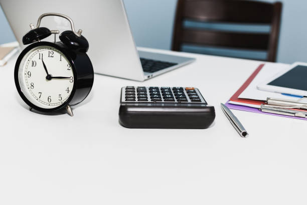 istock retro style black alarm clock with digital laptop computer, calculator, digital mobile tablet and document report on white desk at home office, night working late, business finance, object concept 1227570923
