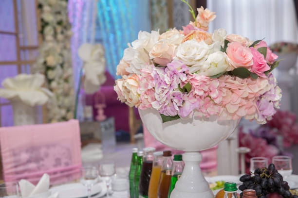 istock wedding table, wedding decorations . Large vase with beautiful roses stands on rich served dinner table .Wedding flower composition for guest . Beautiful pink and white flowers on table in wedding day . 1227570968