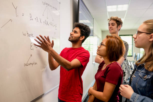 Solving The Problem A man of Indian ethnicity shows his classmates his working out on the white board during a maths class in University in Perth, Australia. university students australia stock pictures, royalty-free photos & images