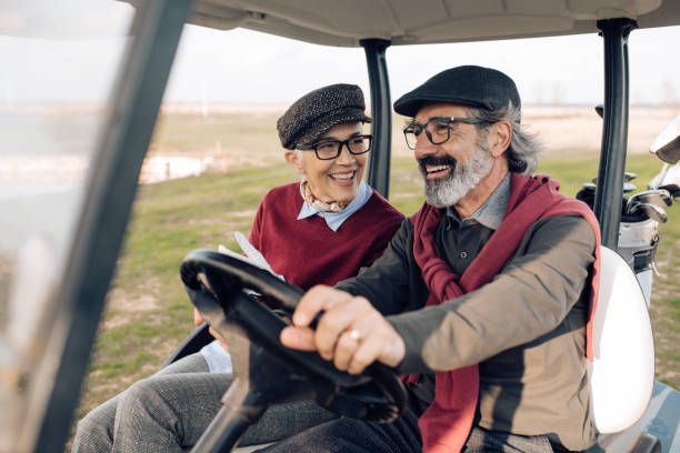 ゴルフカートに乗りながら楽しむシニアカップル - golf cart golf bag horizontal outdoors ストックフォトと画像