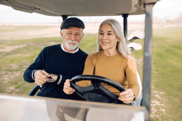 ゴルフカートを運転し、彼女の夫と楽しむシニア女性 - golf cart golf bag horizontal outdoors ストックフォトと画像