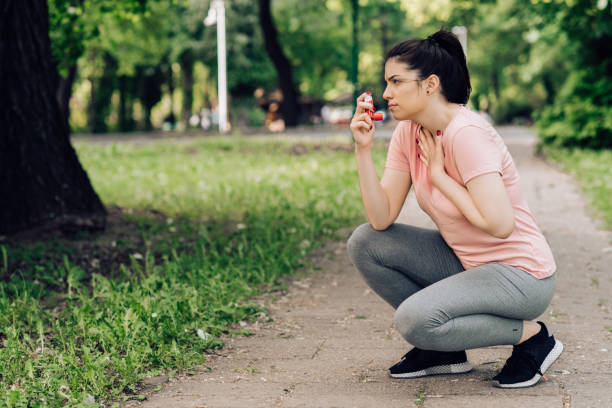 Girl using asthma inhaler during jogging Girl using asthma inhaler during jogging in the park. asthma stock pictures, royalty-free photos & images